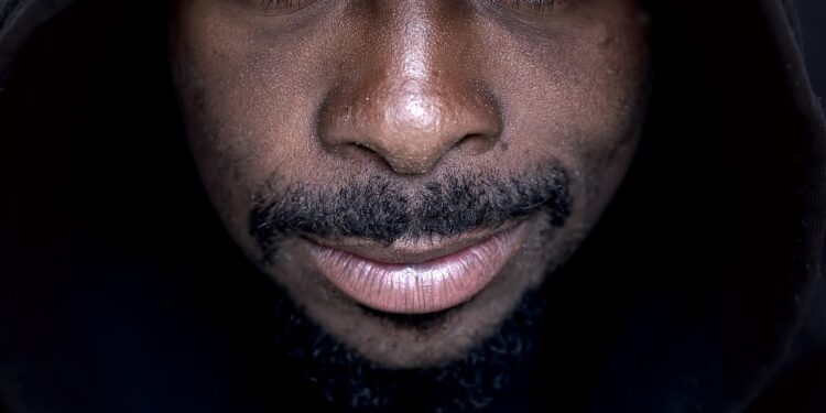 Man with slight smile wearing a black hoodie looking directly at the camera