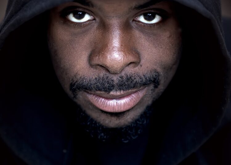 Man with slight smile wearing a black hoodie looking directly at the camera