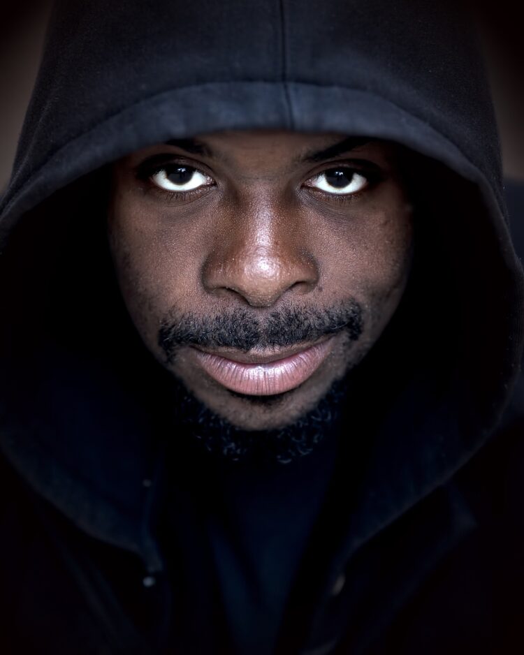 Man with slight smile wearing a black hoodie looking directly at the camera